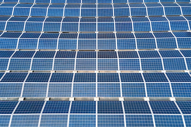 Widok z lotu ptaka elektrowni słonecznej z niebieskimi panelami fotowoltaicznymi zamontowanymi na dachu budynku przemysłowego do produkcji zielonej ekologicznej energii elektrycznej. Produkcja koncepcji zrównoważonej energii.