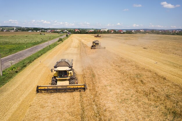 Widok z lotu ptaka kombajny do zbioru duże żółte dojrzałe pole pszenicy.