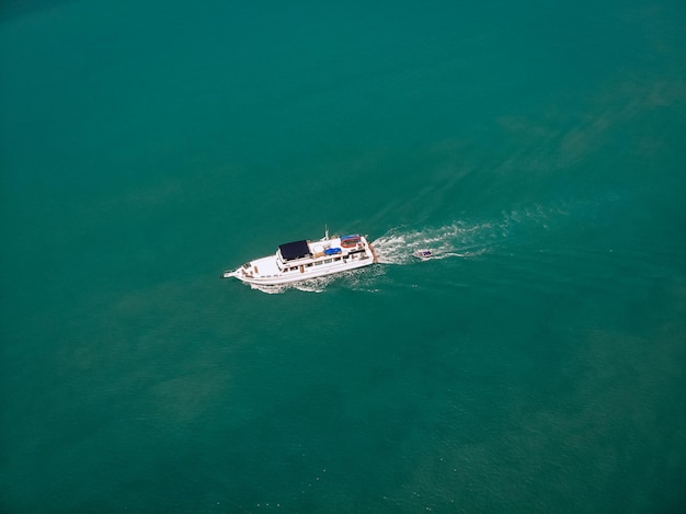 Widok z lotu ptaka łodzi motorowej i łodzi za nią żeglugi w pobliżu wybrzeża Tajlandii, biały ślad na wodzie; koncepcja statków.