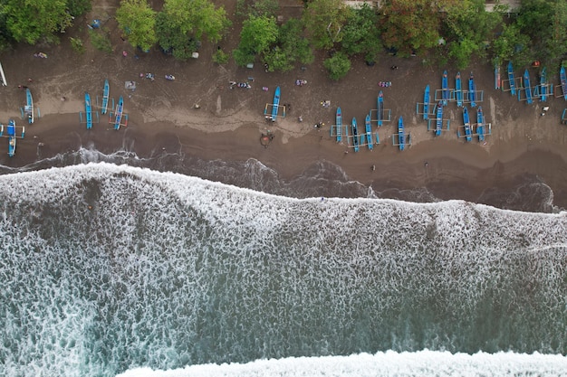 widok z lotu ptaka łodzi rybackich zakotwiczonych na czarnej, piaszczystej plaży. fale oceanu. Plaża Pangandarańska.