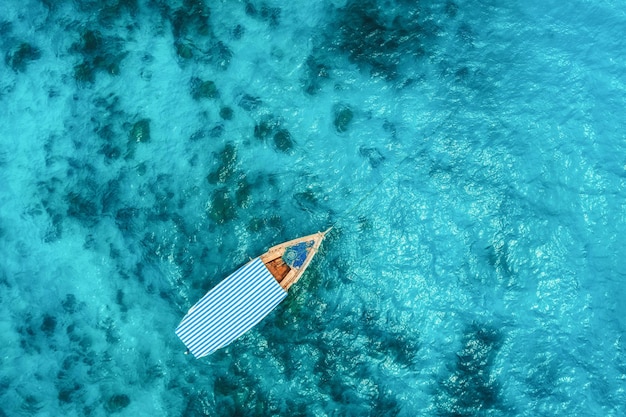 Widok z lotu ptaka łodzi rybackiej w czystej, błękitnej wodzie w słoneczny letni dzień Widok z góry z drona łodzi na Oceanie Indyjskim w Afryce Zanzibar Krajobraz z motorówką przezroczyste morze Pejzaż morski