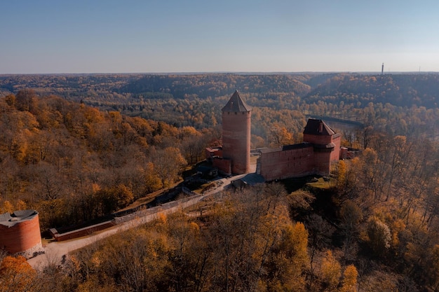 Zdjęcie widok z lotu ptaka miasta sigulda na łotwie podczas złotej jesieni. średniowieczny zamek w środku lasu.