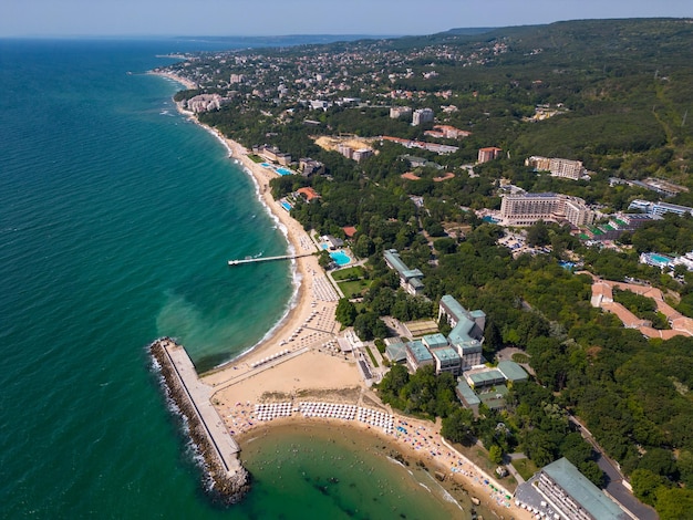 Widok z lotu ptaka na bułgarski kurort Złote Piaski w sezonie letnim, szereg basenów hotelowych i tłumy ludzi cieszących się morzem
