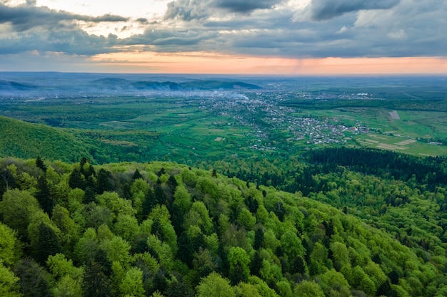 Widok z lotu ptaka na ciemne górskie wzgórza pokryte zieloną sosną mieszaną i bujnym lasem wieczorem.