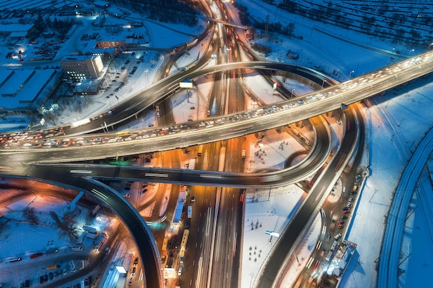 Widok z lotu ptaka na drogę w nowoczesnym mieście w nocy w zimie Widok z góry ruchu na skrzyżowaniu autostrad z oświetleniem Podwyższona droga i wiadukt wymiany Ruchliwe skrzyżowanie Droga ekspresowa i autostrada
