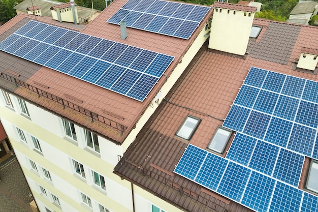 Widok z lotu ptaka na elektrownię słoneczną z niebieskimi panelami fotowoltaicznymi zamontowanymi na dachu budynku mieszkalnego.