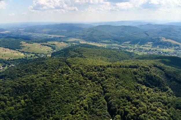 Widok z lotu ptaka na górskie wzgórza pokryte gęstymi, zielonymi, bujnymi lasami w jasny letni dzień