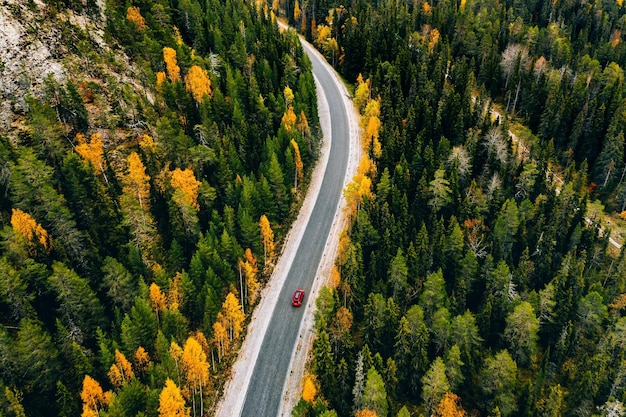 Widok Z Lotu Ptaka Na Jesienny Kolor Lasu W Górach I Drogę Z Czerwonym Samochodem W Finlandii Laponia