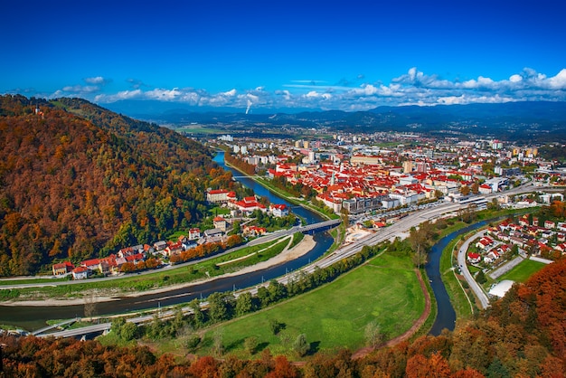 Widok z lotu ptaka na miasto Celje w Słowenii. Jesienne drzewa, zielone łąki i czerwone dachy. Tło podróży na świeżym powietrzu.