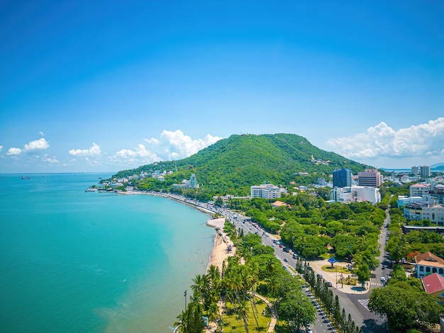 Widok z lotu ptaka na miasto Vung Tau z pięknym zachodem słońca i tyloma łodziami Panoramiczny widok na wybrzeże Vung Tau z góry z falami Wybrzeża ulice drzewa kokosowe i góra Tao Phung w Wietnamie