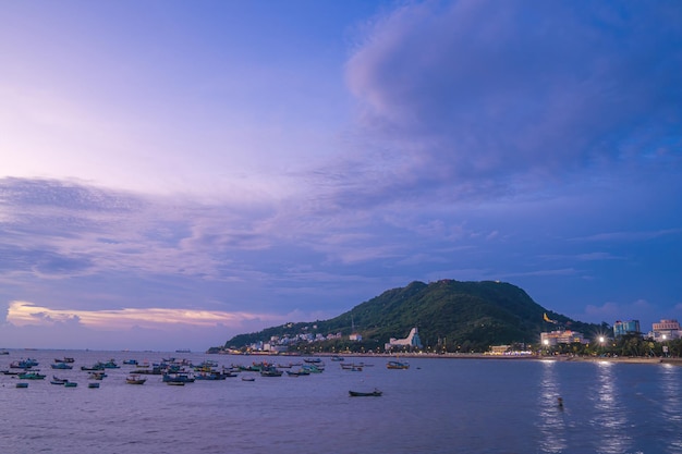 Widok z lotu ptaka na miasto Vung Tau z pięknym zachodem słońca i tyloma łodziami Panoramiczny widok na wybrzeże Vung Tau z góry z falami Wybrzeża ulice drzewa kokosowe i góra Tao Phung w Wietnamie