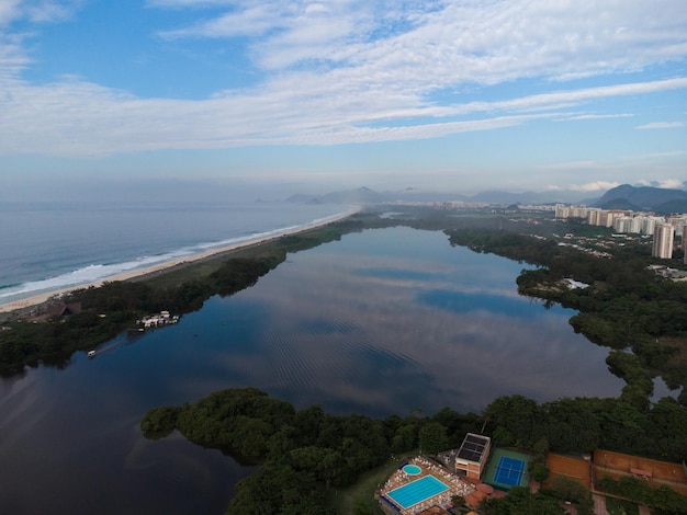 Widok z lotu ptaka na plażę Reserva i lagunę Marapendi. W tle wzgórza Recreio dos Bandeirantes w Rio de Janeiro w Brazylii. Świt. Słoneczny dzień z chmurami. Zdjęcie z drona.