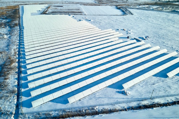 Widok z lotu ptaka na pokrytą śniegiem, zrównoważoną elektrownię z rzędami paneli fotowoltaicznych do produkcji czystej energii elektrycznej Niska efektywność odnawialnej energii elektrycznej w północnej zimie