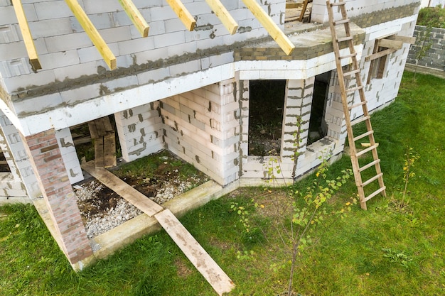 Widok z lotu ptaka na prywatny dom z ceglanymi ścianami z betonu komórkowego i drewnianą ramą na przyszły dach.