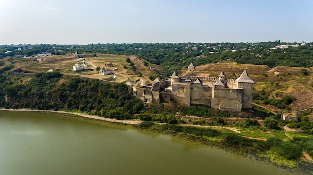 Widok z lotu ptaka na średniowieczny zamek Chocim na zielonym wzgórzu nad rzeką.