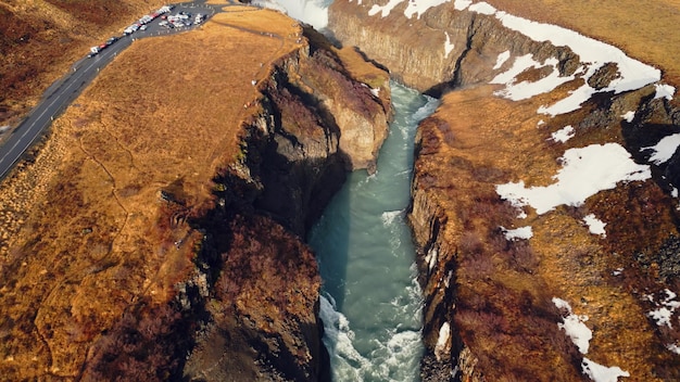 Widok z lotu ptaka na wodospad rzeki Gullfoss, piękna zimna woda przepływająca między zamarzniętymi ośnieżonymi wzgórzami i polami. Islandzka przyroda i nordycka sceneria w pobliżu kaskady. Zwolnione tempo.