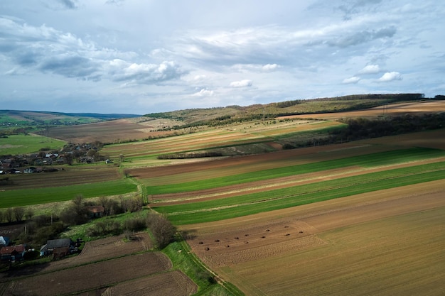 Widok z lotu ptaka na zaorane pola uprawne z żyzną glebą uprawną przygotowaną do sadzenia roślin między zielonymi lasami na wiosnę