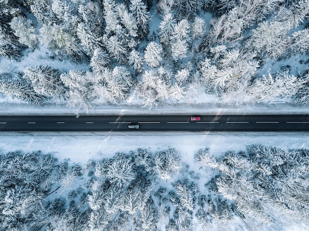 Widok z lotu ptaka na zimową drogę i las z pokrytymi śniegiem drzewami w Finlandii widok z góry