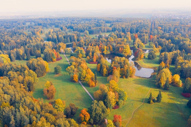 Widok z lotu ptaka nad jesiennym parkiem doliny z łąkami i krętą rzeką, stawami, jasnymi drzewami.