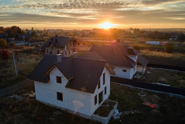 Widok z lotu ptaka niedokończonego domu ze ścianami z betonu komórkowego i drewnianą ramą dachu pokrytą metalowymi płytkami w budowie.