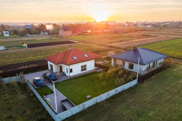 Widok z lotu ptaka prywatnych domów na wiejskich obszarach podmiejskich o zachodzie słońca.