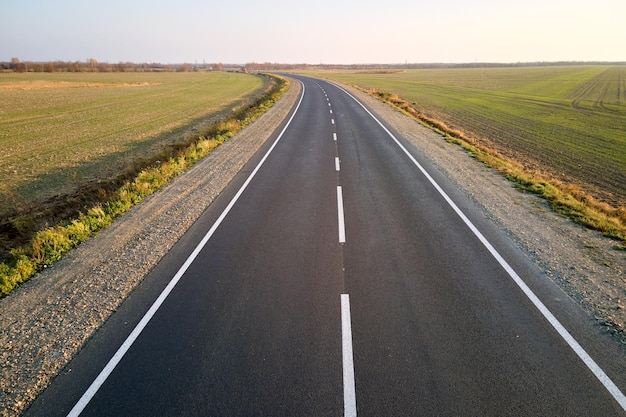 Widok z lotu ptaka pustej drogi międzymiastowej o zachodzie słońca. Widok z góry z drona autostrady w godzinach wieczornych.