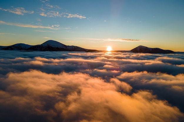 Widok z lotu ptaka tętniącego życiem wschodu słońca nad białą gęstą mgłą z odległych ciemnych Karpat na horyzoncie.