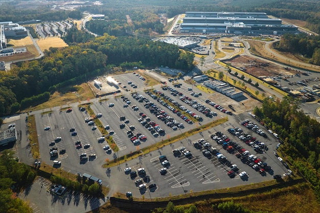 Widok z lotu ptaka wielu samochodów pracowniczych zaparkowanych na parkingu przed budynkiem fabryki przemysłowej