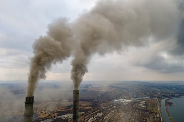 Zdjęcie widok z lotu ptaka wysokich rur elektrowni węglowej z czarnym dymem w górę zanieczyszczającej atmosfery.