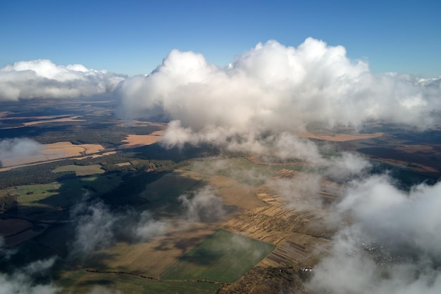 Widok z lotu ptaka z okna samolotu na dużej wysokości ziemi pokrytej białymi, puszystymi chmurami cumulus