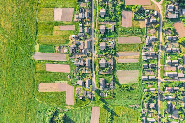 Widok z lotu ptaka z wysokości wsi z domami i ulicami zaoranymi latem polami łąkami