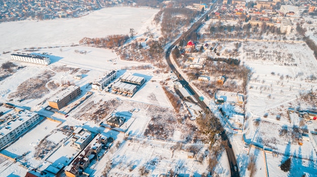 Widok z lotu ptaka zimą z góry na dół wysoko nad wiejskim powolnym życiem przy małej rzece.