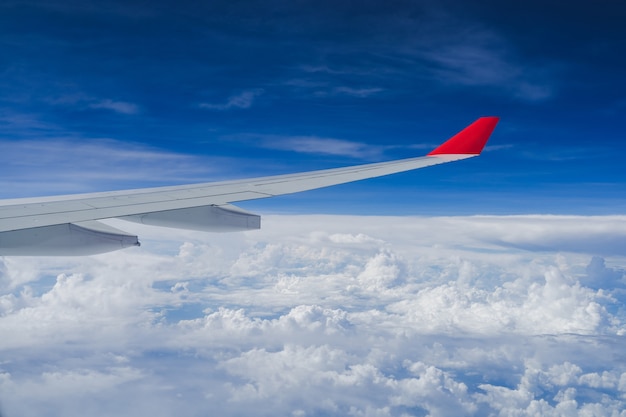 Widok z okna samolotu i skrzydła z puszystymi chmurami, latanie i podróżowanie