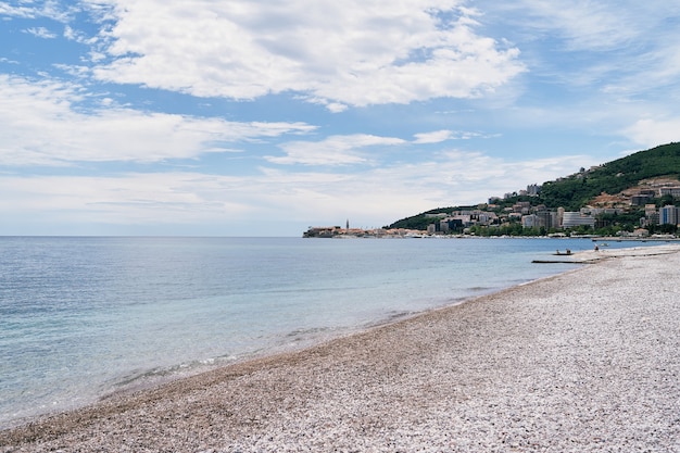 Widok z plaży na zieleń gór i budynki na tle nieba