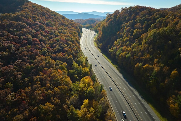 Widok z powietrza autostrady I40 w Północnej Karolinie prowadzącej do Asheville przez góry Apalaczy w złotej jesieni z szybko poruszającymi się ciężarówkami i samochodami Koncepcja transportu międzystanowego