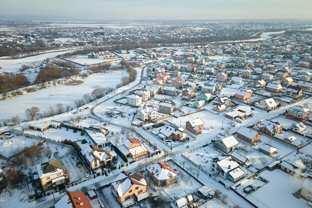 Zdjęcie widok z powietrza domów mieszkalnych z pokrytymi śniegiem dachami na przedmieściach wiejskich miast zimą