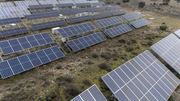 Widok z powietrza dużej zrównoważonej elektrowni z wieloma rzędami paneli słonecznych fotowoltaicznych do produkcji czystej energii elektrycznej o zachodzie słońca