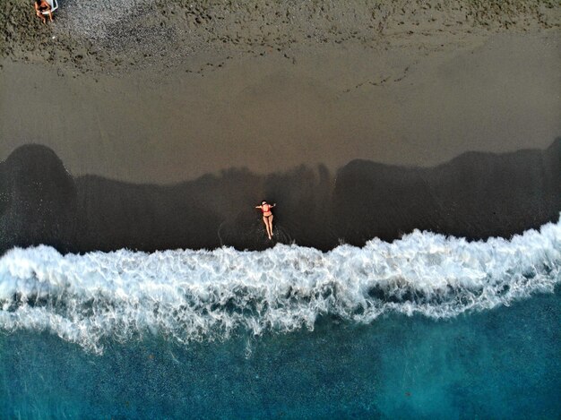 Zdjęcie widok z powietrza kobiety odpoczywającej na plaży.
