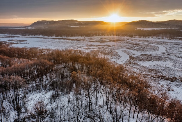 Widok z powietrza na śnieżne pole i góry przy zachodzie słońca