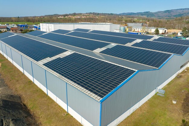 Widok z powietrza niebieskich paneli słonecznych fotowoltaicznych zamontowanych na dachu budynku przemysłowego do produkcji zielonej, ekologicznej energii elektrycznej Produkcja koncepcji zrównoważonej energii