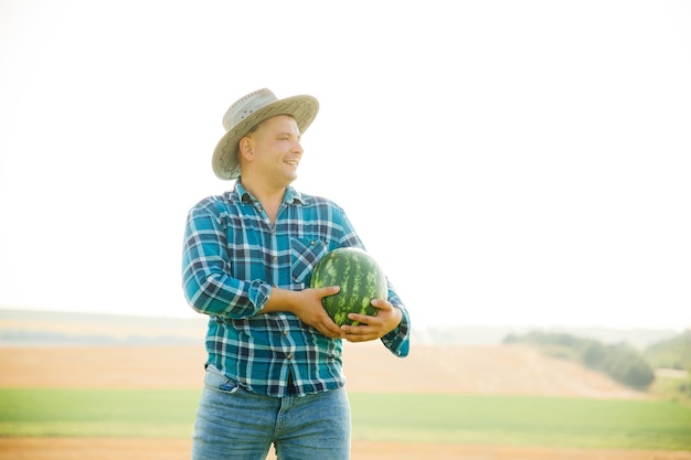 Widok z profilu rolnika mężczyzna z arbuzem w ramionach mężczyzna w kapeluszu ubrany w niebieską koszulę z...