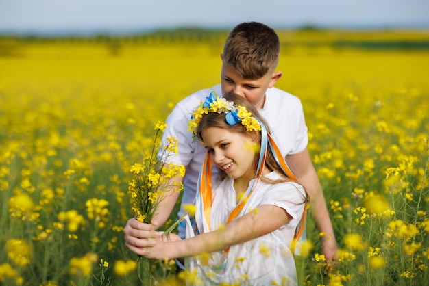 Zdjęcie widok z przodu braci i siostry dzieci idących daleko ścieżką z trawą otoczoną żółtymi polami