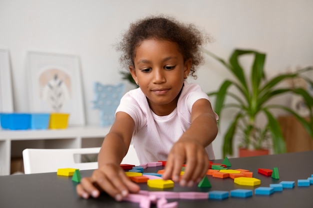 Zdjęcie widok z przodu dziewczyna układająca puzzle przy stole