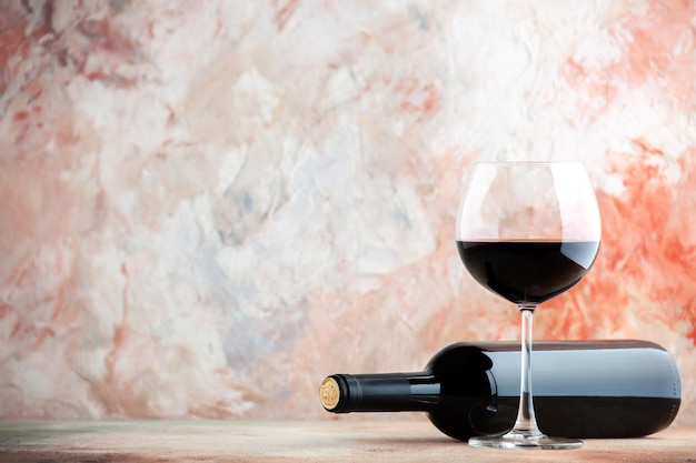 Widok z przodu kieliszek wina z butelką na jasnym tle alkohol napój lemoniada obiad zdjęcie winogronowy wakacyjny bar