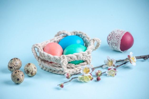 widok z przodu kolorowe malowane jajka wewnątrz lin na niebieskiej powierzchni ozdobna wiosenna koncepcja etniczne wakacje kolorowe