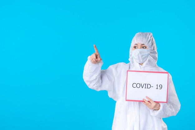 widok z przodu lekarka w kombinezonie ochronnym i masce na niebieskim tle kolor covid- izolacja zdrowotna pandemia wirus nauk medycznych
