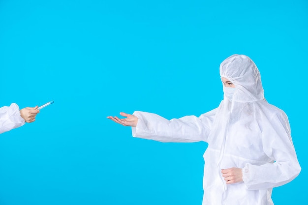 widok z przodu lekarki w kombinezonach ochronnych i maskach trzymających kolby na niebieskim tle szpital medyczny nauka o zdrowiu covid-wirus