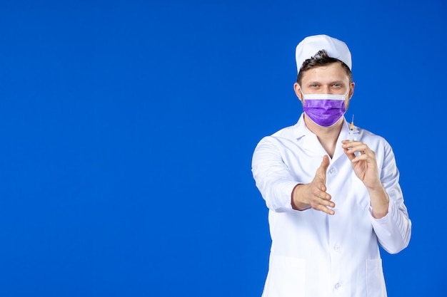 Widok z przodu lekarza płci męskiej w garniturze i fioletowej masce gospodarstwa zastrzyk na niebiesko