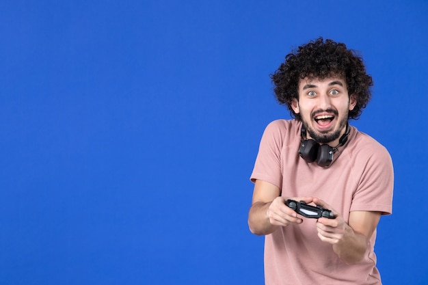 widok z przodu męski gracz grający w grę wideo z gamepadem na niebieskim tle wygrywający nastolatek dorosły gracz piłka nożna radość młoda sofa młodzież