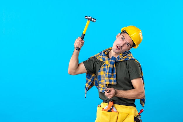 widok z przodu mężczyzna budowniczy w kasku trzymający śrubokręt i młotek na niebieskim tle praca domowa pracownik architektura płaski budynek